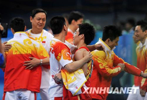 8月9日，中国选手邹凯（左四）和教练相拥庆祝。当日，中国队在北京奥运会体操男子资格赛第二场的比赛中，以374.675分的总成绩暂列资格赛第一。