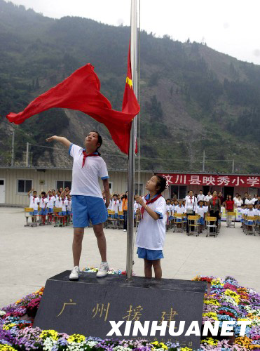 8月27日，映秀小学学生在板房校园内升起鲜艳的五星红旗。 新华社发