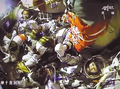 昨日，天宫一号与神十飞船成功实现手控交会对接。3位航天员手拉手庆祝成功（摄自北京航天飞控中心大屏幕）。新华社发（张晓祺 摄）