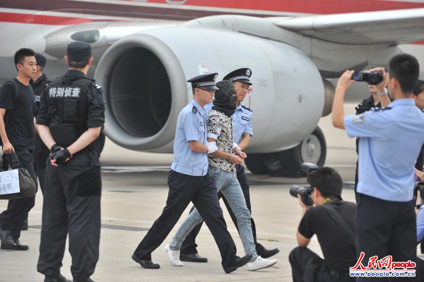 “5·16”跨国电信诈骗案犯罪嫌疑人被警方带下飞机。(人民网记者 翁奇羽摄)