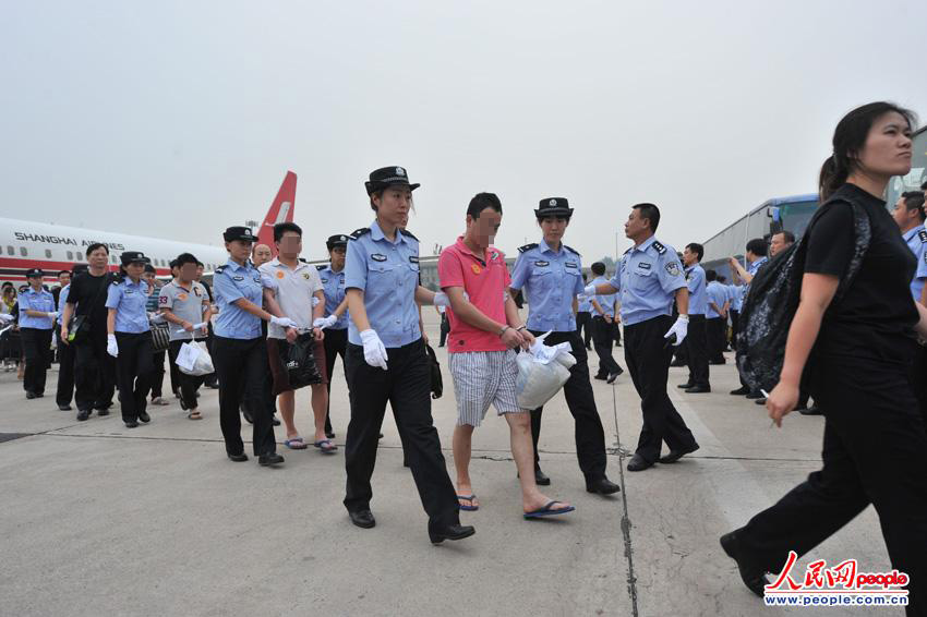 “5·16”跨国电信诈骗案犯罪嫌疑人被警方带下飞机。(人民网记者 翁奇羽摄)