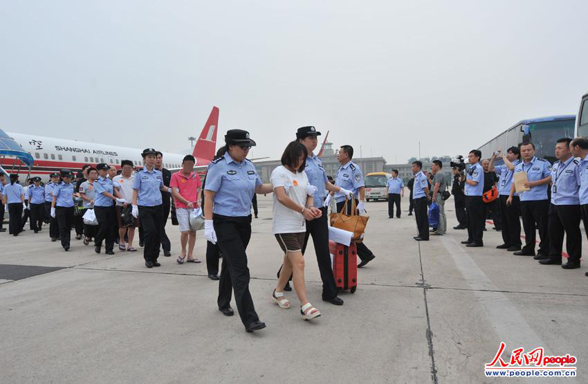 “5·16”跨国电信诈骗案犯罪嫌疑人被警方带下飞机。(人民网记者 翁奇羽摄)