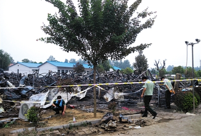 昨日，河南省鲁山县，康乐园老年公寓失火后，被烧毁的彩钢板房只剩下骨架，火场勘查人员（左一）正在工作。