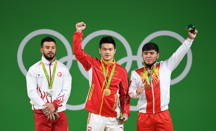 8月9日，中国选手石智勇（中）、土耳其选手伊斯梅洛夫（左）和吉尔吉斯斯坦选手阿尔特科夫在颁奖仪式上。当日，在2016年里约奥运会举重男子69公斤级决赛中，中国选手石智勇以352公斤的总成绩夺冠。土耳其选手伊斯梅洛夫和吉尔吉斯斯坦选手阿尔特科夫分获亚军、季军。新华社记者程敏摄 