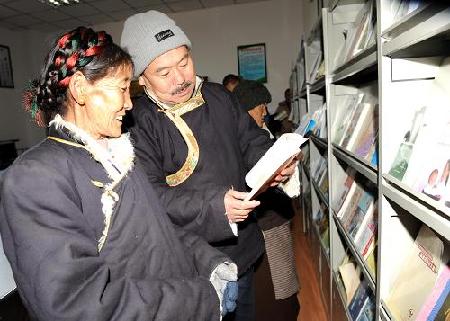拉萨市城关区热木齐居委会居民索朗塔杰（左）等在农家书屋看书