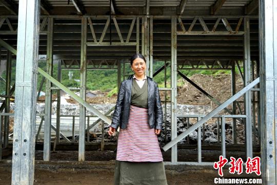 西藏隆子县玉麦乡位于中印边境，是中国人口最少的行政乡，全乡56户农牧民将于今年搬迁至新房。图为7月14日，玉麦乡群宗站在框架已经搭建好的新房门前，喜笑颜开。　江飞波 摄