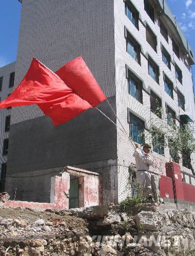  7月5日，一名防化兵高举红旗在北川县城内行走。当日，记者经特许进入地震重灾区北川县城采访，用相机记录下北川县城的现状。 